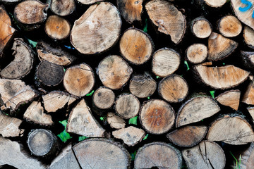 Background of dry chopped firewood logs stacked up on top of each other in a pile.