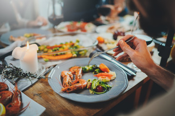 Festive table. Cropped image of best friends dining together at home, healthy mediterranean food, selective focus on dish with prawns and zucchini paste, Holidays Dinner Family Celebrate Concept