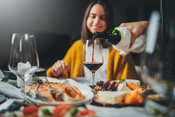 Romantic couple enjoying dinner at restaurant, concept love, waiter pouring red wine for woman, relationship and romantic, happy couple celebrating at home
