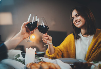 Romantic dinner, beautiful young couple having dinner drinking red wine in restaurant, best friends making cheers with glasses of wine enjoying homemade food, sweet couple dining by candlelight