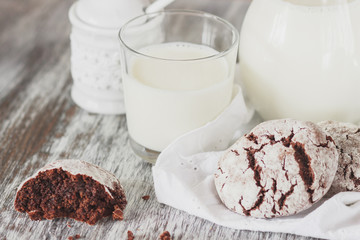 Handmade chocolate cookies, glass and jug with milk, blurred background