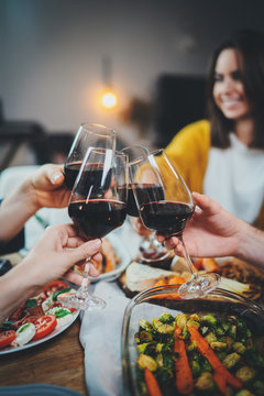Vertical image of happy friends cheering with wine glasses at home, family celebrate anniversary enjoying healthy homemade food, Dinner Enjoyment Holidays Friendship Concept
