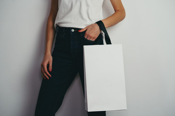 Young hipster girl holding blank shopping bag, mock-up of white paper package, online shopping...
