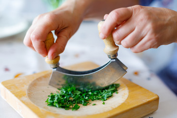 A woman shreds parsley on a wooden cutting board in the kitchen