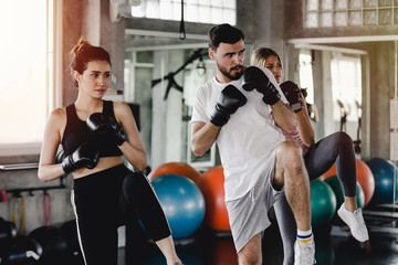 Sporty woman and men with the back boxing gloves training at the gym