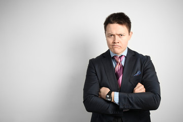 Young attractive guy businessman in suit on gray with skeptic expression nervously standing.