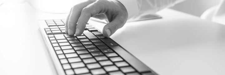Black and white image of male hand using computer keyboard