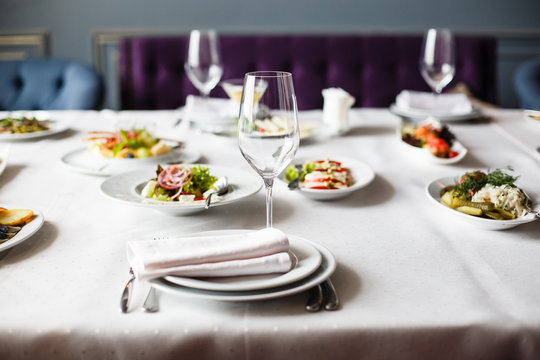 Served For Banquet Restaurant Table With Dishes, Snack, Cutlery, Wine And Water Glasses, European Food, Selective Focus