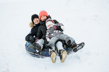 Happy family having fun outdoor. Child, mother and father playing in winter time. Active healthy lifestyle concept