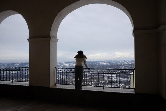 girl at the balcony looks at snowy landscape