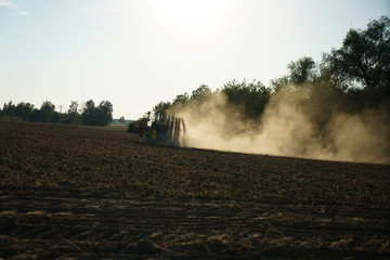 Fototapeta na wymiar Just before sunset, a farmer was still working on a dusty field 