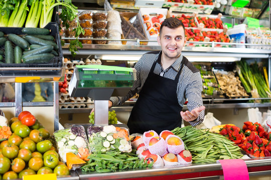 cheerful male seller showing assortment of grocery shop