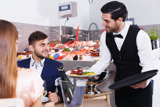 Waiter bringing seafood to guests