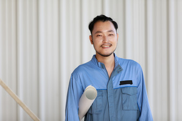 Obraz premium Portrait of male engineer with self-confidense and friendly manner, holding roll paper in hand