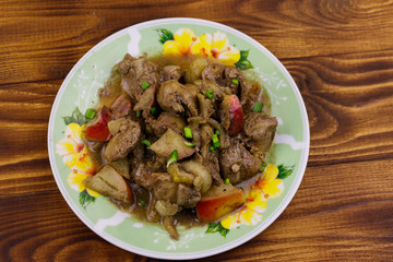 Stewed chicken liver with apple and onion on wooden table