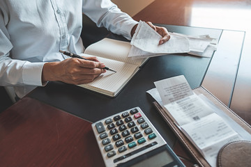 Woman with bills and calculator. Woman using calculator to calculate bills at the table in office....