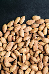 Natural background made in nuts. Black and stone background with almonds.