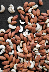 Natural background made in nuts. Cashews and almonds on black background.