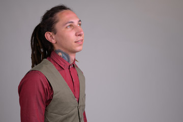 Face of young happy businessman with dreadlocks thinking