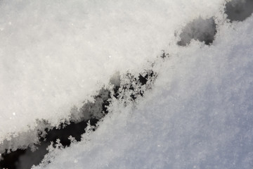 deep dark crack in clear sparkling snow cover