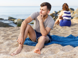 Fototapeta na wymiar Man sitting with displeasure on the beach
