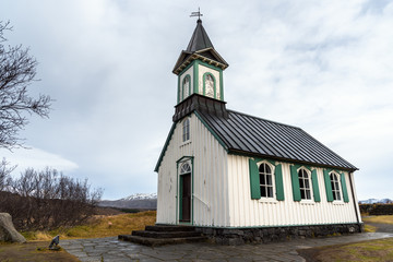 Fototapeta na wymiar Historic White Wooden Chapel with Green Shutters in Iceland on a Cloudy Autumn Day