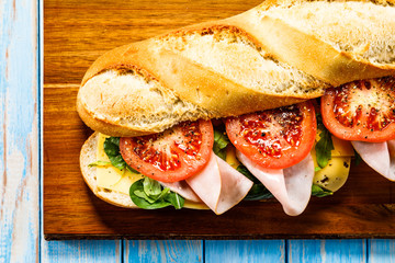 Long sandwich on cutting board on wooden table