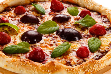 Pizza with plums and strawberries on white background
