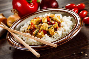 Grilled meat, white rice and vegetables on wooden table