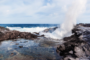 Waves breaking on the rocky coast of the Canary Islands. Tourism, travel, vacation, sea cruise.