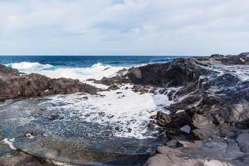 Obraz premium Waves breaking on the rocky coast of the Canary Islands. Tourism, travel, vacation, sea cruise.
