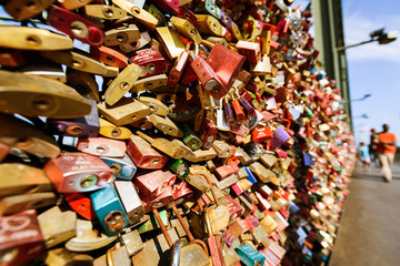 Love locks on a bridge, people in bokeh on background