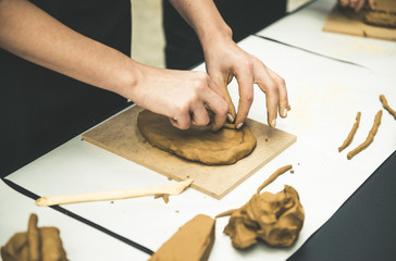 Female mask works with clay, craftsman hands close up