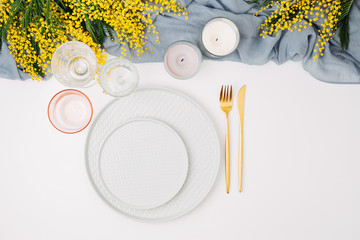 Festive table setting. Plates and cutlery with gray decorative textile and yellow flowers on white...