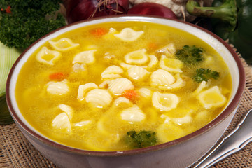 Clear soup with chicken and noodles. Broth with carrots, onions various fresh vegetables in a pot