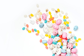 Easter candy chocolate eggs and Jellybean flowing from party paper bag on white background