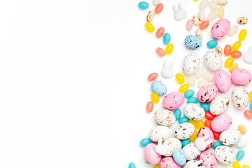 Easter candy chocolate eggs and Jellybean flowing from party paper bag on white background