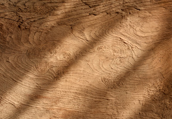 Rustic texture of wooden floor shaded by afternoon sunlight through window.
