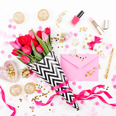 Pink and Gold Styled Desk with Florals. Pink tulips in black and white stylish wrapping paper, gifts, cosmetics and female accessories with confetti on white background