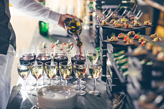 The waiter pours wine into glasses. Event catering concept.