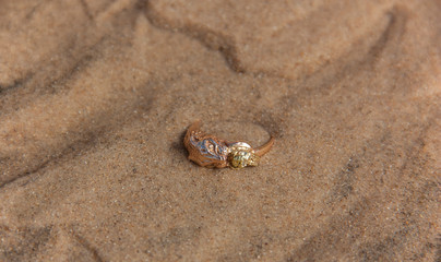 Golden ring lying on the sand under water