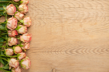 Fototapeta na wymiar Valentine's Day. Frame made of roses flowers on wooden background. Valentine's day background. Flat lay, top view, copy space