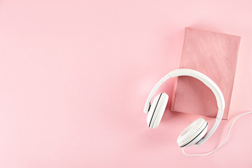 Electronic audiobook vs regular paper book concept. Stack of different color hardcover books with blank colorful covers & white headphones on table. Old versus new. Close up, copy space, background.