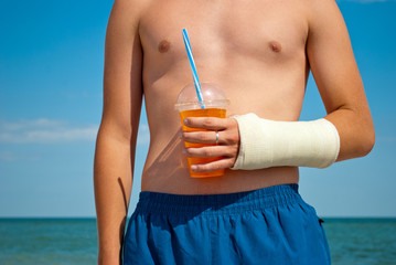 Gypsum fracture on a man's hand, cocktail juice orange, sand close-up against the background of the...
