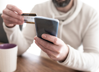 close-up of man entering credit card information while shopping on the internet on smartphone