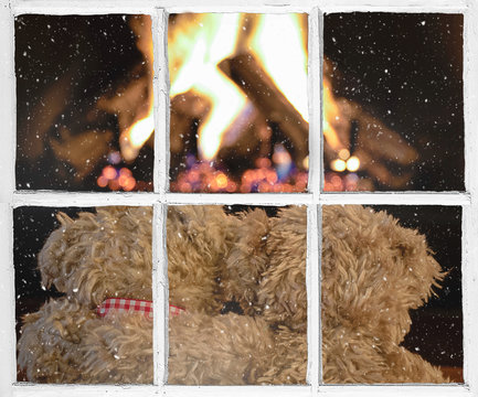 pair of brown teddy bears in front of fireplace snowflakes on windowpane