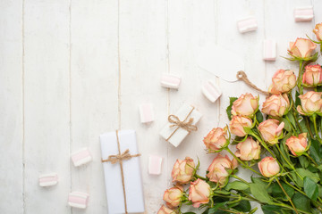 Pink roses on a white wooden background with sweets, festive background, anniversary, wedding, Valentine's Day.Flat lay.top view, copy space
