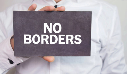 Man showing No Borders text in cardboard.