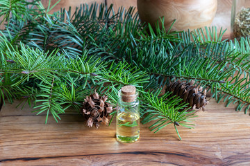 A bottle of Douglas fir essential oil with Douglas fir branches