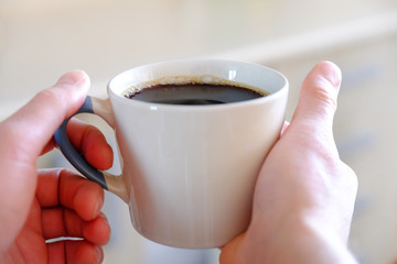 Mug of morning hot coffee. In the hands of close-up